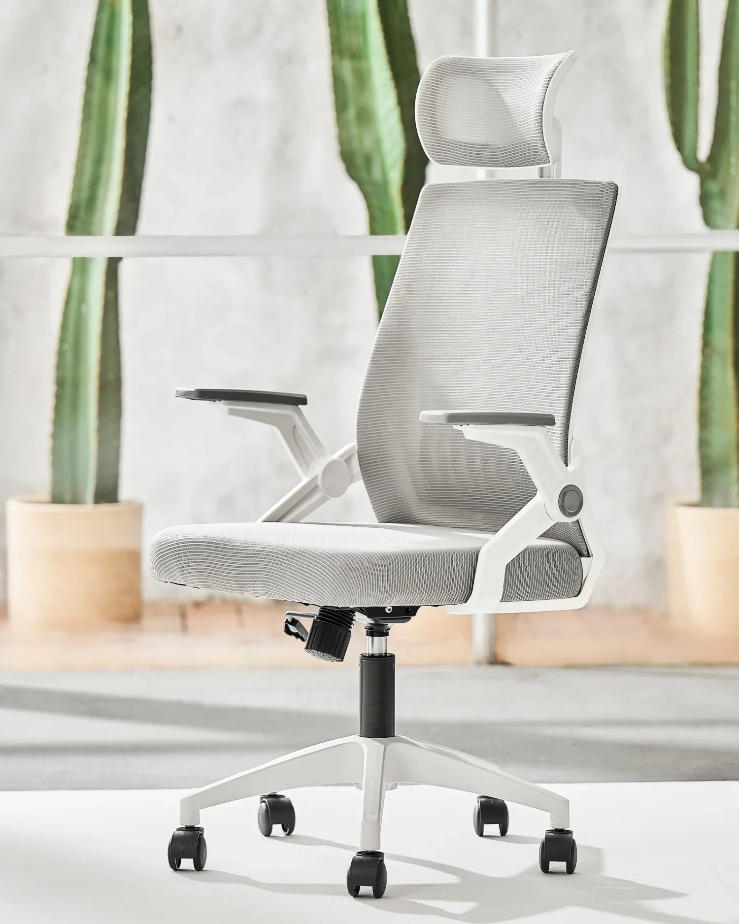Silla ejecutiva ergonómica con tapizado gris y estructura blanca en un ambiente moderno