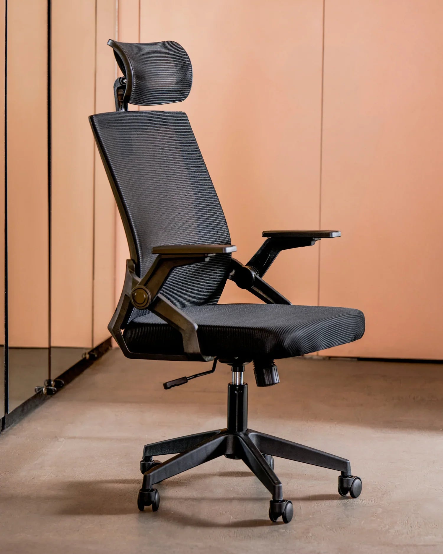 Silla ejecutiva ergonómica negra con respaldo de malla en un espacio de oficina moderno